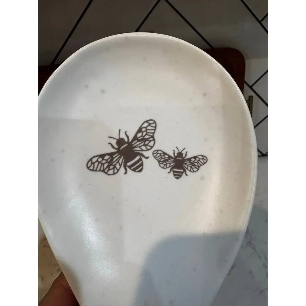 white ceramic spoon rest black bee graphic contrasting brown dipped handle